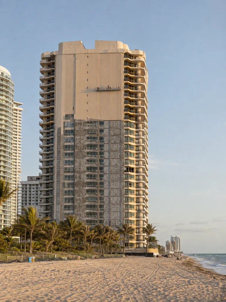 Full view of an oceanfront tower being repainted, seen from the beach