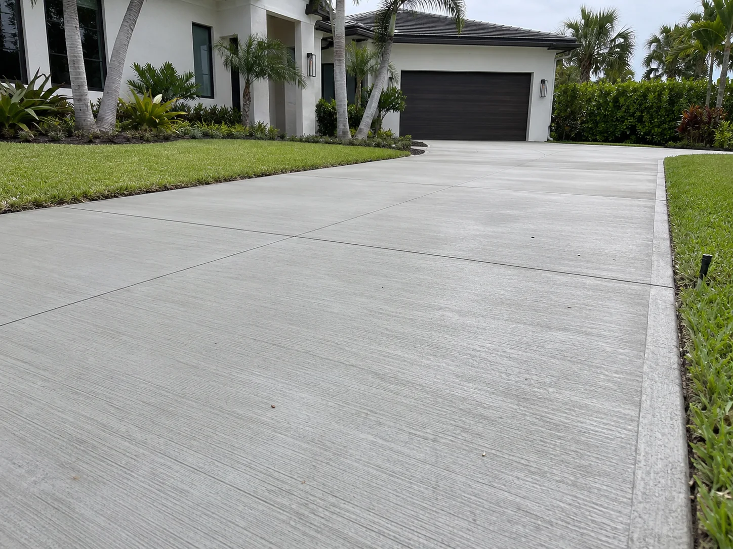 Finished concrete driveway with broom finish and saw-cut control joints at a Miami home