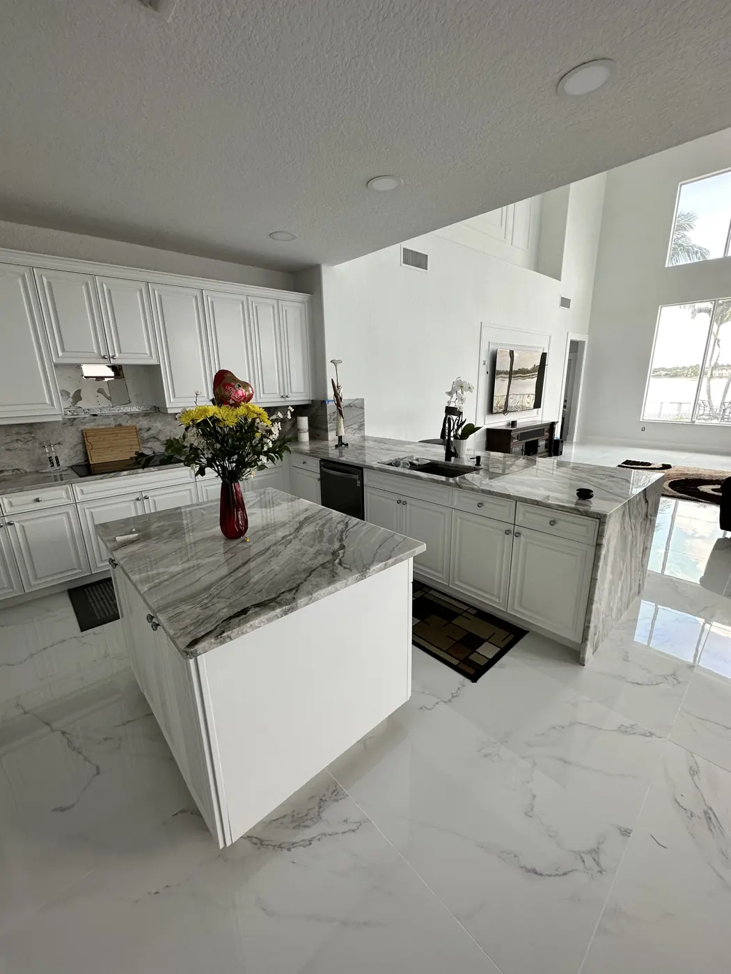 Remodeled kitchen with white cabinets and a marble-look stone island in a South Florida house